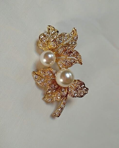 Broche bisuteria dorado con forma de hojas similes blancos y perlas.Nuevo