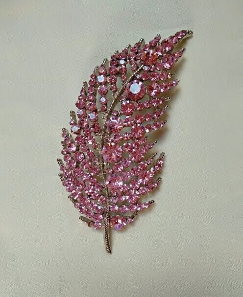 Broche bisuteria plateado en forma de hoja cuajado de piedras color rosa.Nuevo